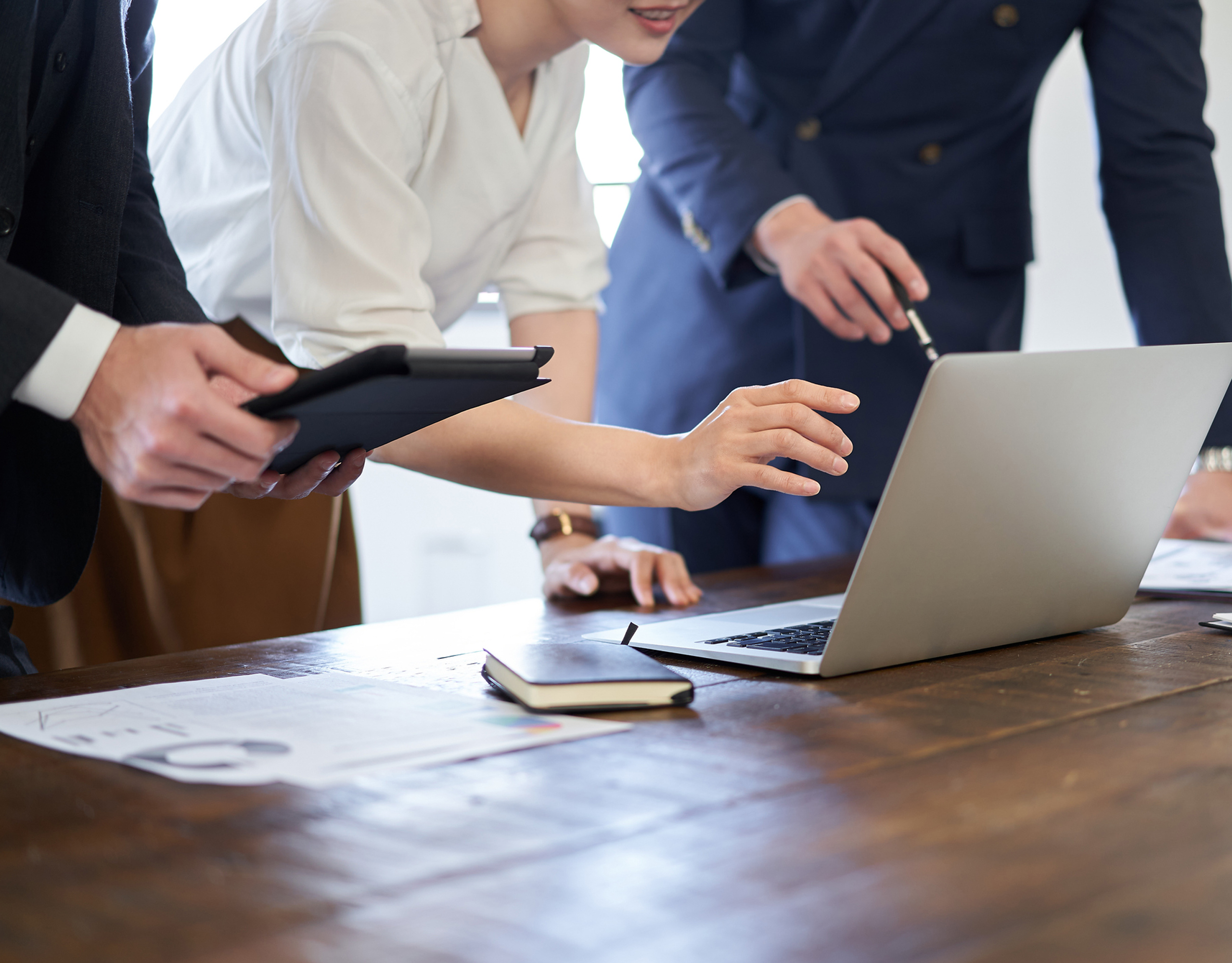 Team collaborating over a laptop and tablet in a modern office.