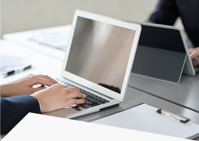 Hands typing on a laptop in office.